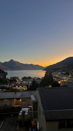 the sun is setting over some houses and mountains in the distance, as seen from an apartment balcony