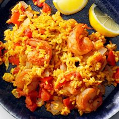 a plate with rice, shrimp and lemon wedges on the side next to a slice of lemon