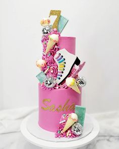 a pink birthday cake with ice cream cones, candy and decorations on the top tier