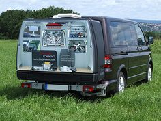 a van is parked in the middle of a grassy field