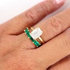 a woman's hand with an emerald and diamond ring