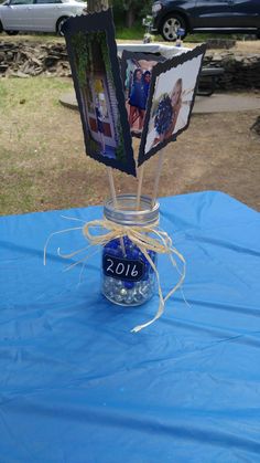 a glass jar with pictures in it sitting on a blue table cloth covered tablecloth