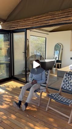 a man sitting on top of a wooden deck next to a glass sliding door in a room