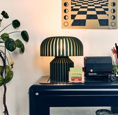 a lamp sitting on top of a blue table next to a plant and other items