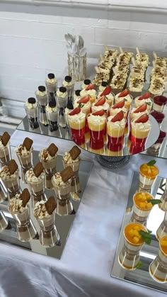 a table topped with lots of desserts and pastries on top of silver trays