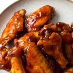 chicken wings covered in bbq sauce on a white plate