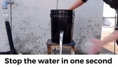 a man standing next to a black trash can on top of a step ladder with water coming out of it