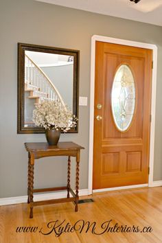 a vase with flowers is sitting on a table in front of a door and mirror