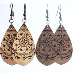 three wooden earrings with designs on them hanging from hooks in front of a white background