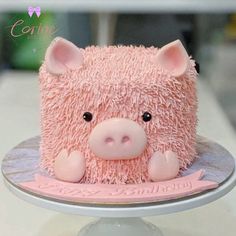 a cake shaped like a pig sitting on top of a white plate with pink frosting