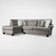 a gray sectional couch with pillows on it's back and side facing each other