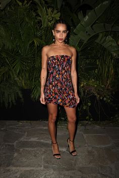 a woman in a strapless dress poses for the camera at an event with palm trees behind her