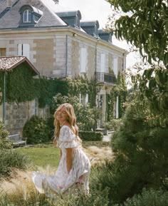 a woman standing in front of a large building with lots of greenery on it