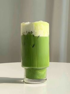 a green vase sitting on top of a white table