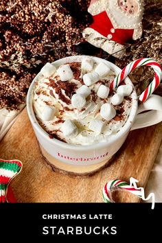 a cup of hot chocolate with marshmallows and candy canes on the side