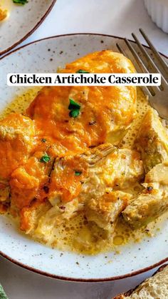 chicken artichoke casserole on a white plate with bread and parsley