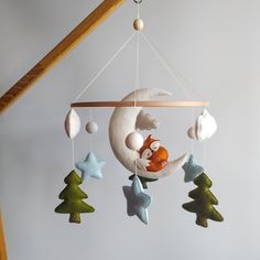 a baby crib mobile with a fox sleeping on the moon and stars hanging from it