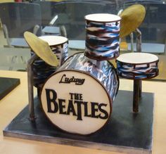 a cake shaped like a drum set with the beatles logo on it