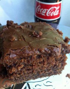 a close up of a piece of cake on a plate with a coca - cola bottle in the background