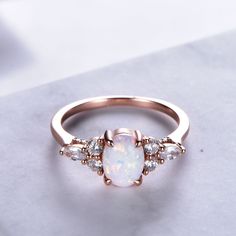 an opal and diamond ring on a white surface with the top view showing it's center stone