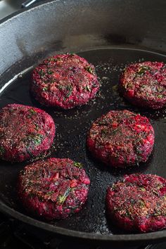 four hamburger patties cooking in a frying pan