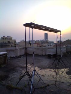 the sun is setting over an old rooftop with some equipment on it and buildings in the background