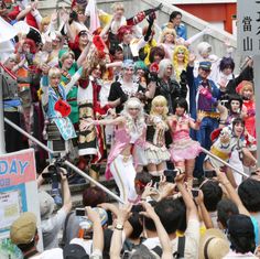 a group of people standing on top of a street next to each other holding up their hands