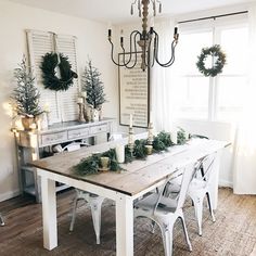 a dining room table decorated for christmas with wreaths and greenery