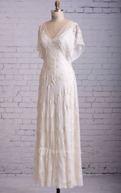 a white wedding dress on a mannequin stand in front of a brick wall