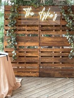 a wooden wall with greenery on it and a sign that says the alke's