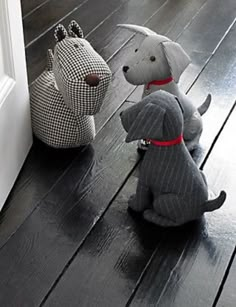 two stuffed dogs sitting next to each other on the floor in front of a door