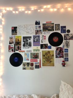 a wall with various records on it and lights strung from the ceiling above them in a bedroom