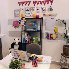 a desk with a laptop computer and a panda bear sitting on it's lap