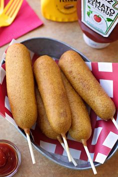 three hotdogs on skewers with ketchup and mustard in the background