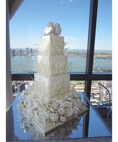 a wedding cake on top of a table in front of a window overlooking the city