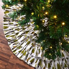 a christmas tree skirt with lights hanging from it's sides on a wooden floor