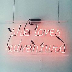 a neon sign with the words she loves adventure on it hanging from a white wall