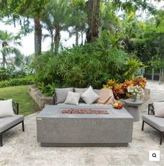 an outdoor fire pit surrounded by chairs and plants