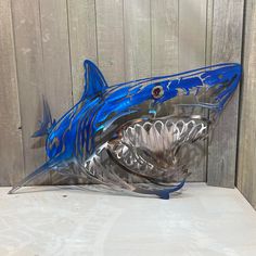 a glass shark sculpture sitting on top of a white table next to a wooden wall