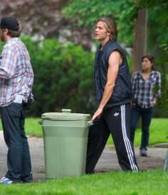 two men are standing next to a trash can