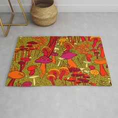 an orange and pink rug with mushrooms on it next to a plant potted basket