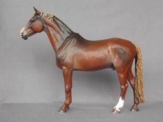 a brown and white horse standing on top of a gray floor next to a wall