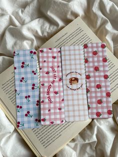 four notebooks are lined up on top of an open book, with cherries printed on them