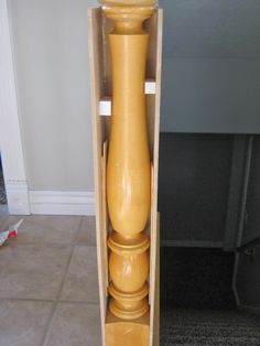 a tall yellow vase sitting inside of a wooden box