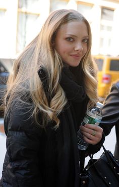 a woman with long blonde hair is holding a drink