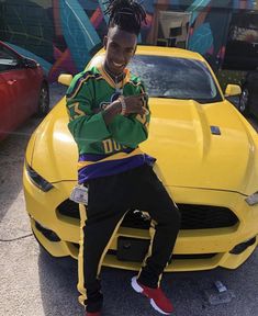 a man sitting on the hood of a yellow sports car