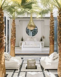 a living room with white couches and palm trees