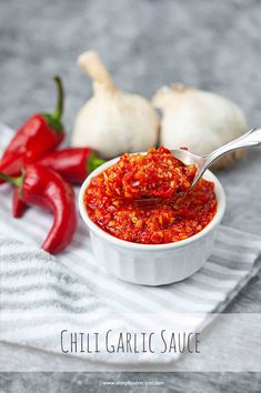 a white bowl filled with chili sauce next to garlic and red peppers