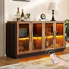 a person holding a remote control in front of a cabinet with wine bottles on it