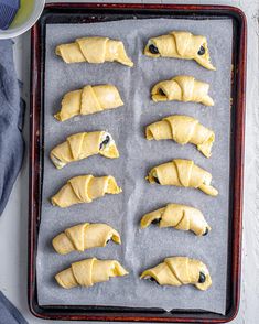 eight pastries on a baking sheet ready to go into the oven with blueberries